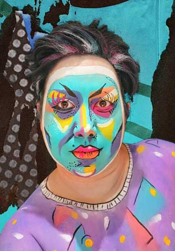 Bild: Caine Panik – Selbstportrait mit sehr intensivem Makeup in knalligen Farben wie ein abstraktes modernes Gemälde, die Gesichtskonturen unterstreichend.